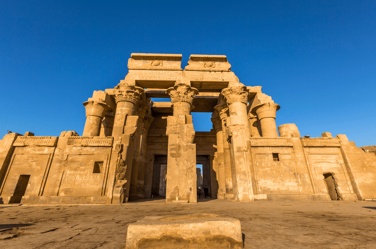 A panoramic view of the Temple of Kom Ombo in Aswan, Egypt, showcasing its double pylons, towering columns, and the Nile River in the background.