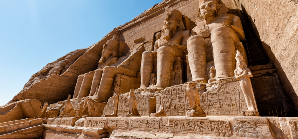 A photo of the Great Temple of Abu Simbel, showcasing the four colossal statues of Ramses II guarding the entrance and the temple's impressive facade carved into the mountainside.