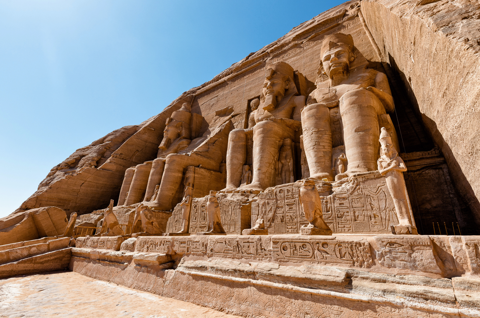  A photo of the Great Temple of Abu Simbel, showcasing the four colossal statues of Ramses II guarding the entrance and the temple's impressive facade carved into the mountainside.