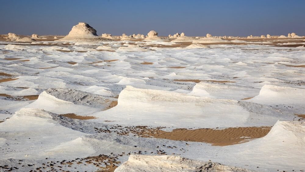 A panoramic view of the White Desert National Park in Egypt, showcasing the white limestone rock formations and the vast desert landscape.