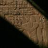 A close-up of a carved stone relief depicting an ancient Egyptian pharaoh holding a ceremonial object.