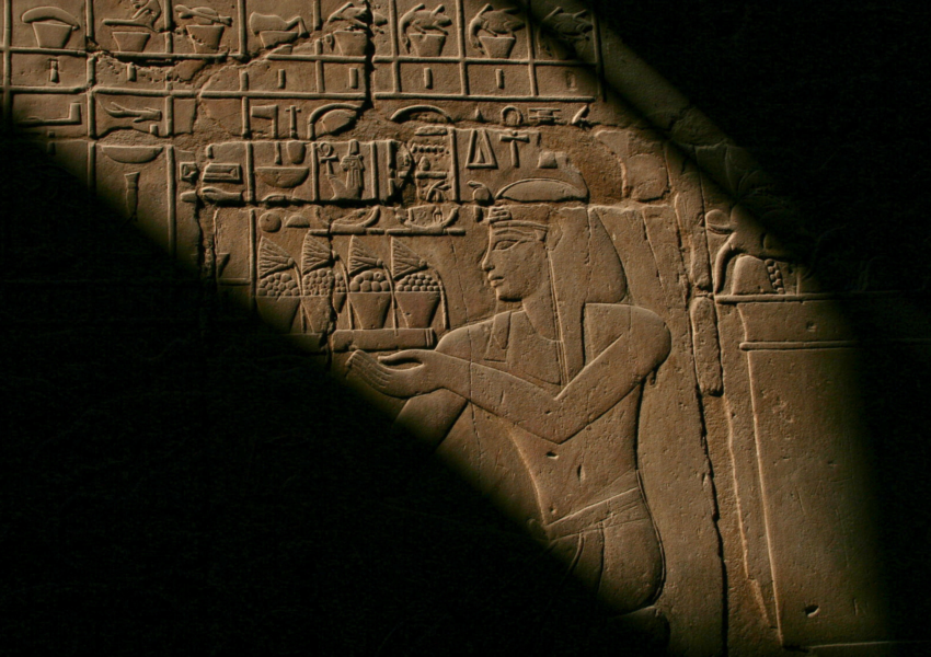 A close-up of a carved stone relief depicting an ancient Egyptian pharaoh holding a ceremonial object.