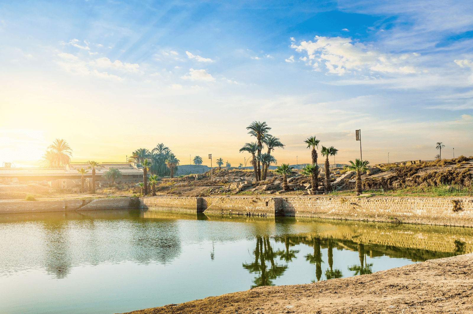 The Sacred Lake, showing the calm water, palm trees, and ancient temple ruins.