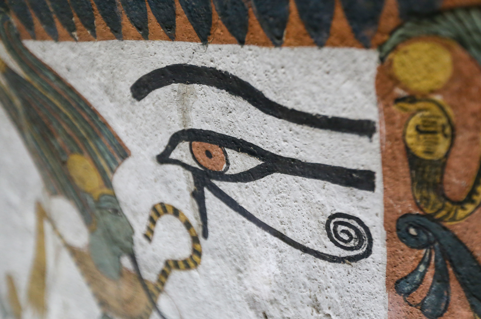 A close-up of an ancient Egyptian wall painting featuring the Eye of Horus symbol, with intricate details and vibrant colors.