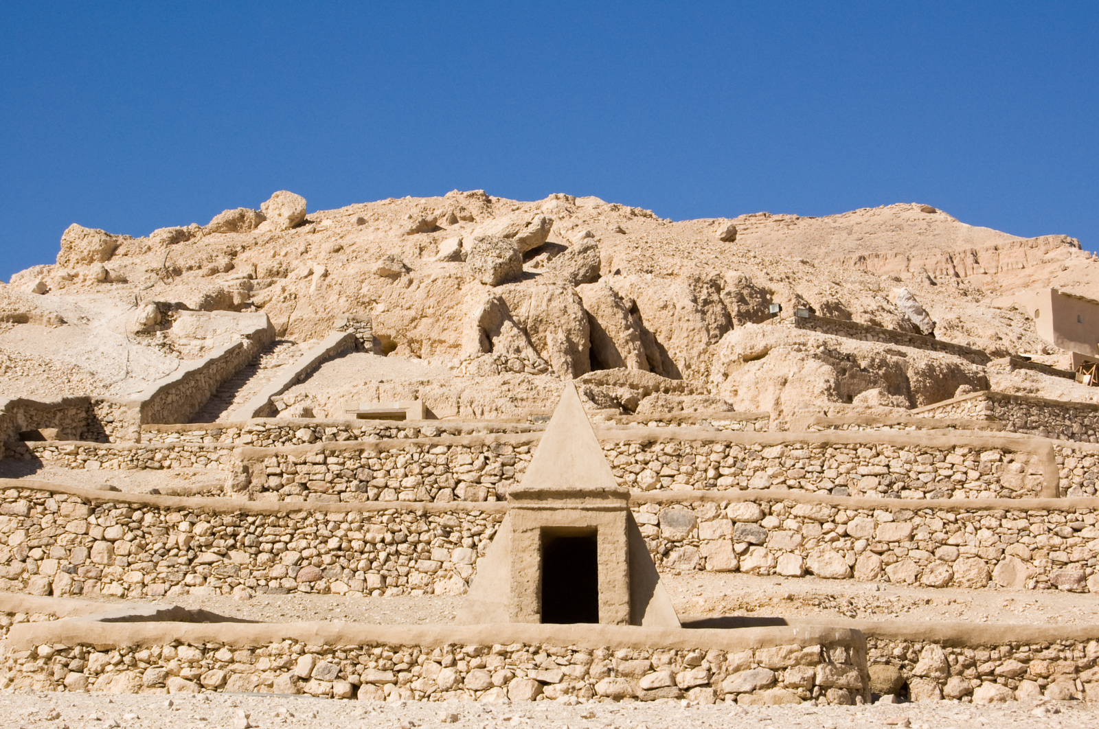 A panoramic view of the Valley of the Nobles in Luxor, Egypt, showcasing the numerous tombs carved into the sandstone cliffs.