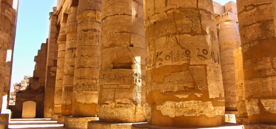 Massive stone columns of Karnak Temple with intricate hieroglyphics.