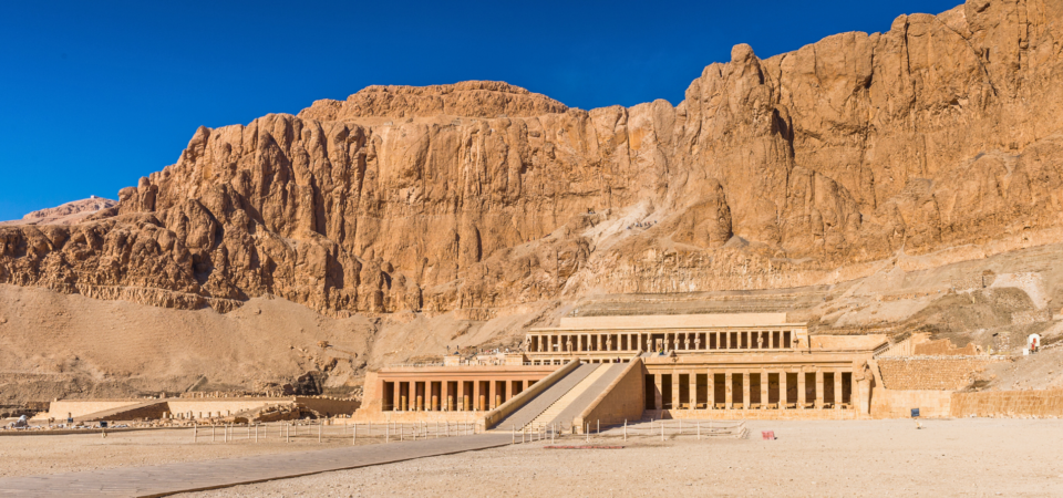 A panoramic view of the Mortuary Temple of Hatshepsut in Deir el-Bahari, showcasing its terraced design and its integration into the surrounding cliffs.