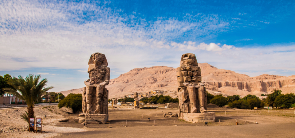 Two colossal statues of Pharaoh Amenhotep III standing in the Valley of the Kings, Luxor, Egypt.