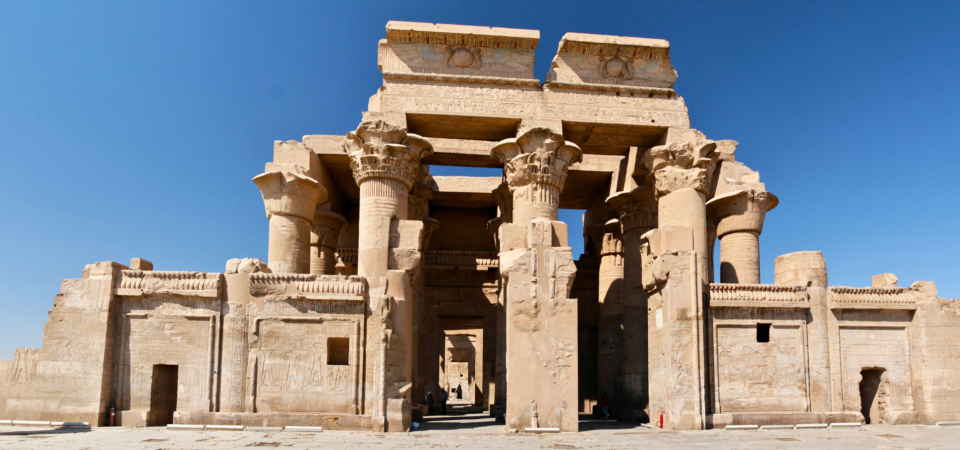 A photo of the entrance to the Temple of Kom Ombo in Aswan, Egypt, showcasing its symmetrical design and the towering hypostyle hall with columns.