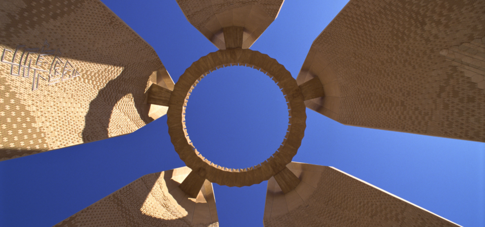 A close-up view of the Egyptian-Soviet Friendship Tower, showcasing its circular design and towering pillars against a blue sky.