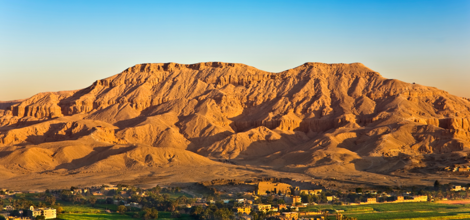 Aerial view of West Bank Luxor at sunrise, with a hot air balloon and Habu Temple below on the right.