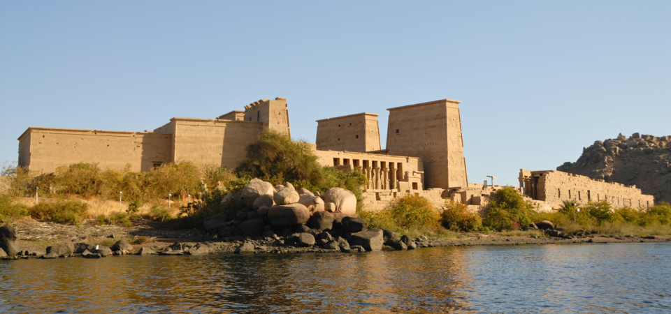 A photo of the Temple of Philae, a historic temple complex located on Agilkia Island in Aswan, Egypt. The temple is surrounded by water and features a large, towering pylon.