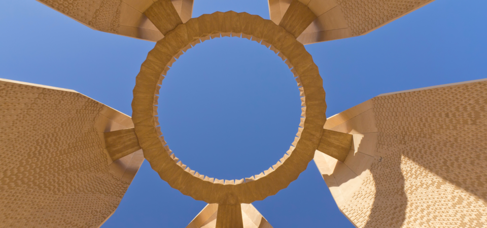 A close-up view of the Egyptian-Soviet Friendship Tower, showcasing its circular design and towering pillars against a blue sky.