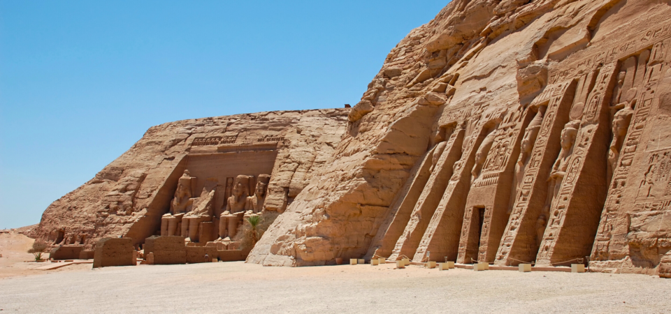 A photo of the Great Temple of Abu Simbel, showcasing the four colossal statues of Ramses II guarding the entrance and the temple's impressive facade carved into the mountainside.