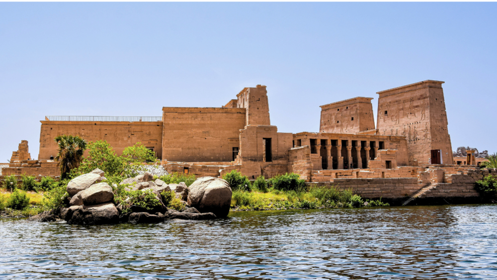 A photo of the Temple of Philae, a historic temple complex located on Agilkia Island in Aswan, Egypt. The temple is surrounded by water and features a large, towering pylon.