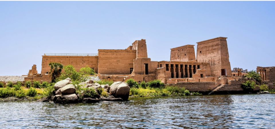 A photo of the Temple of Philae, a historic temple complex located on Agilkia Island in Aswan, Egypt. The temple is surrounded by water and features a large, towering pylon.