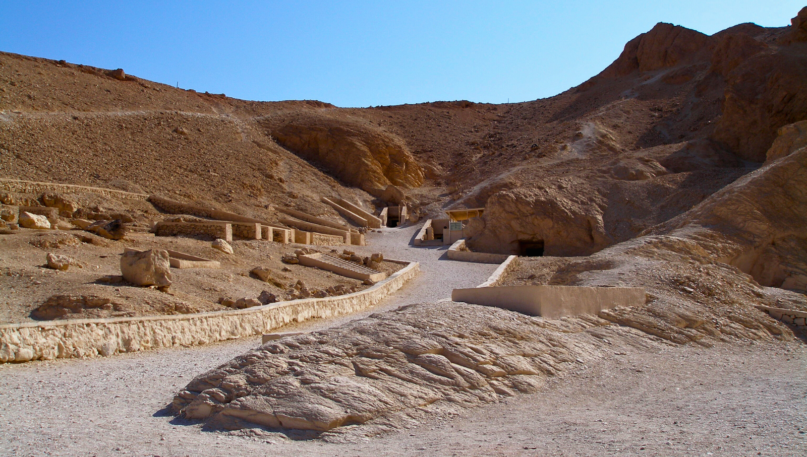 A photo of the Valley of the Queens in Luxor, Egypt, showcasing the numerous tombs carved into the cliffs and the surrounding desert landscape.