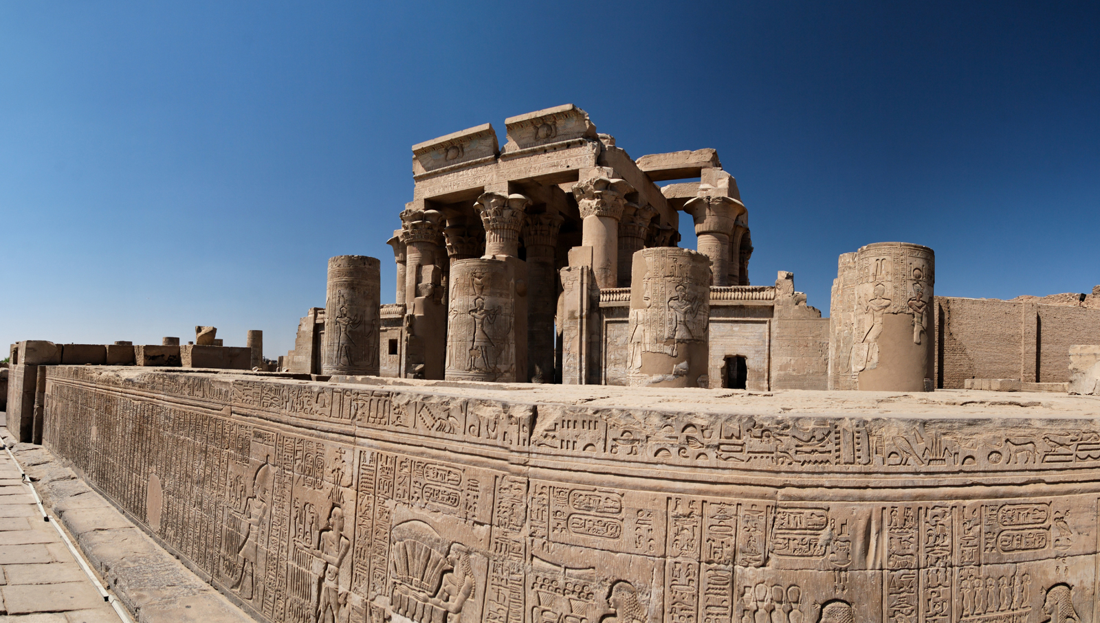 A panoramic view of the Temple of Kom Ombo in Aswan, Egypt, showcasing its double pylons, towering columns, and the intricate hieroglyphics on the walls.