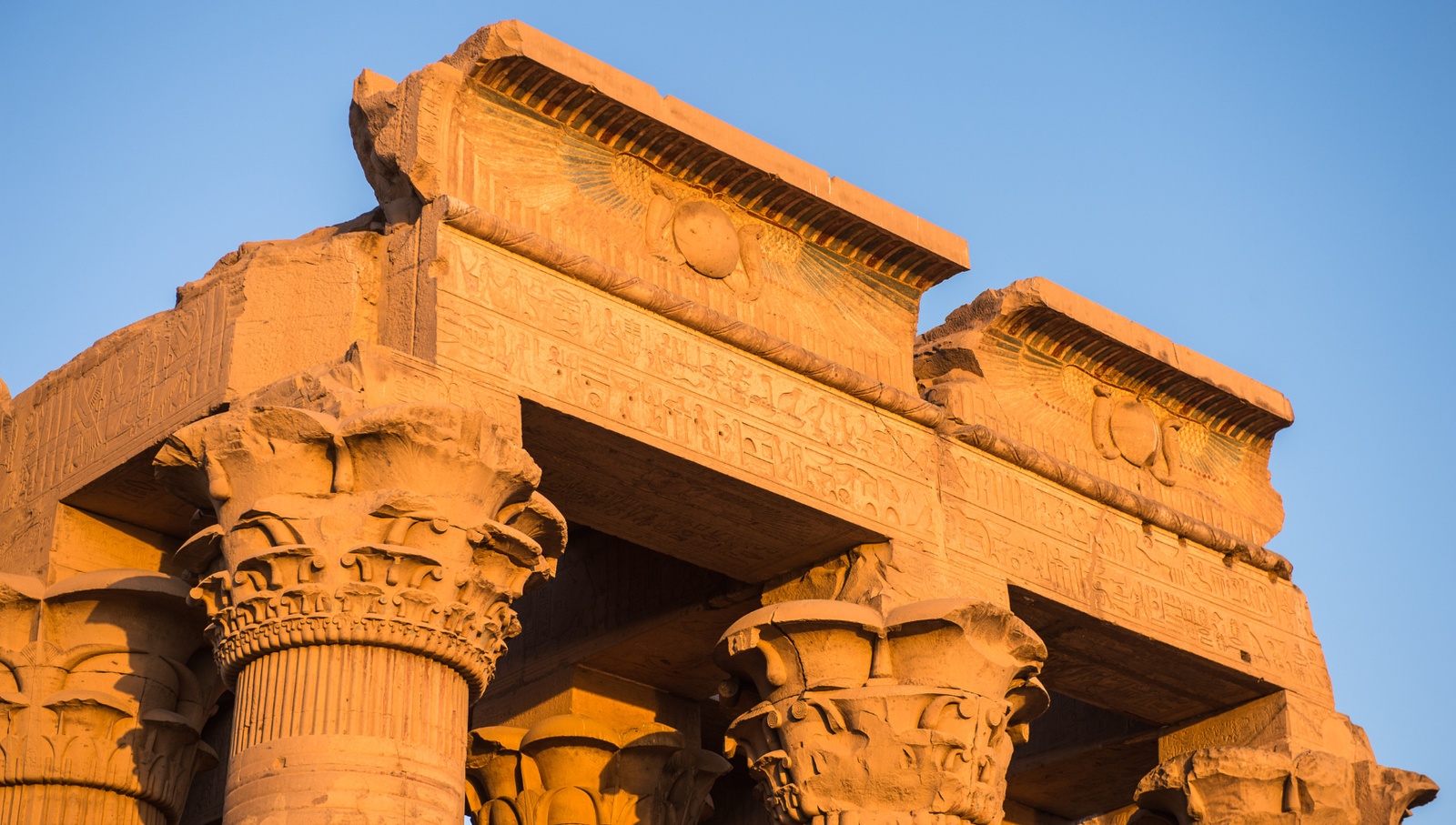 A photo of the Temple of Kom Ombo, showcasing the massive columns, the hieroglyphics on the walls, and the golden hour light.