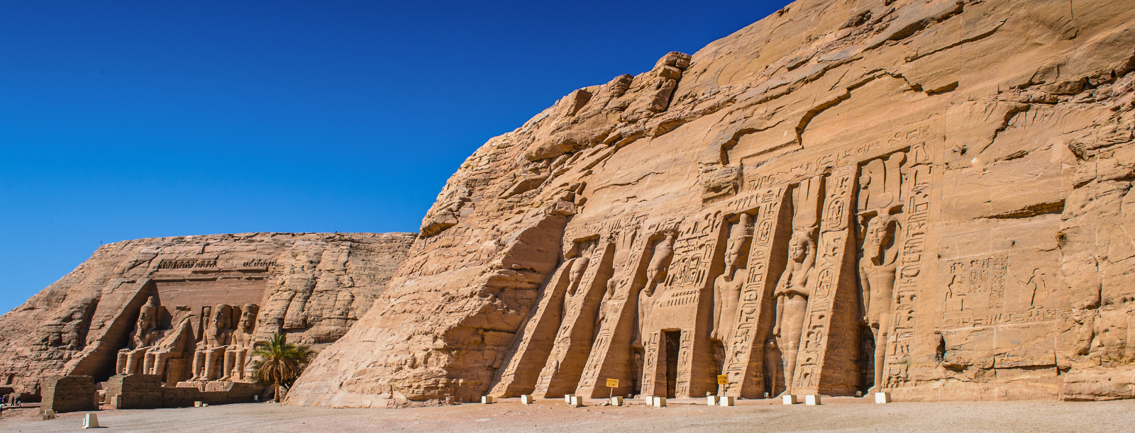 A photo of the Great Temple of Abu Simbel and the Temple of Hathor and Nefertari, showcasing the colossal statues of Ramses II and the temples' facades carved into the mountainside.