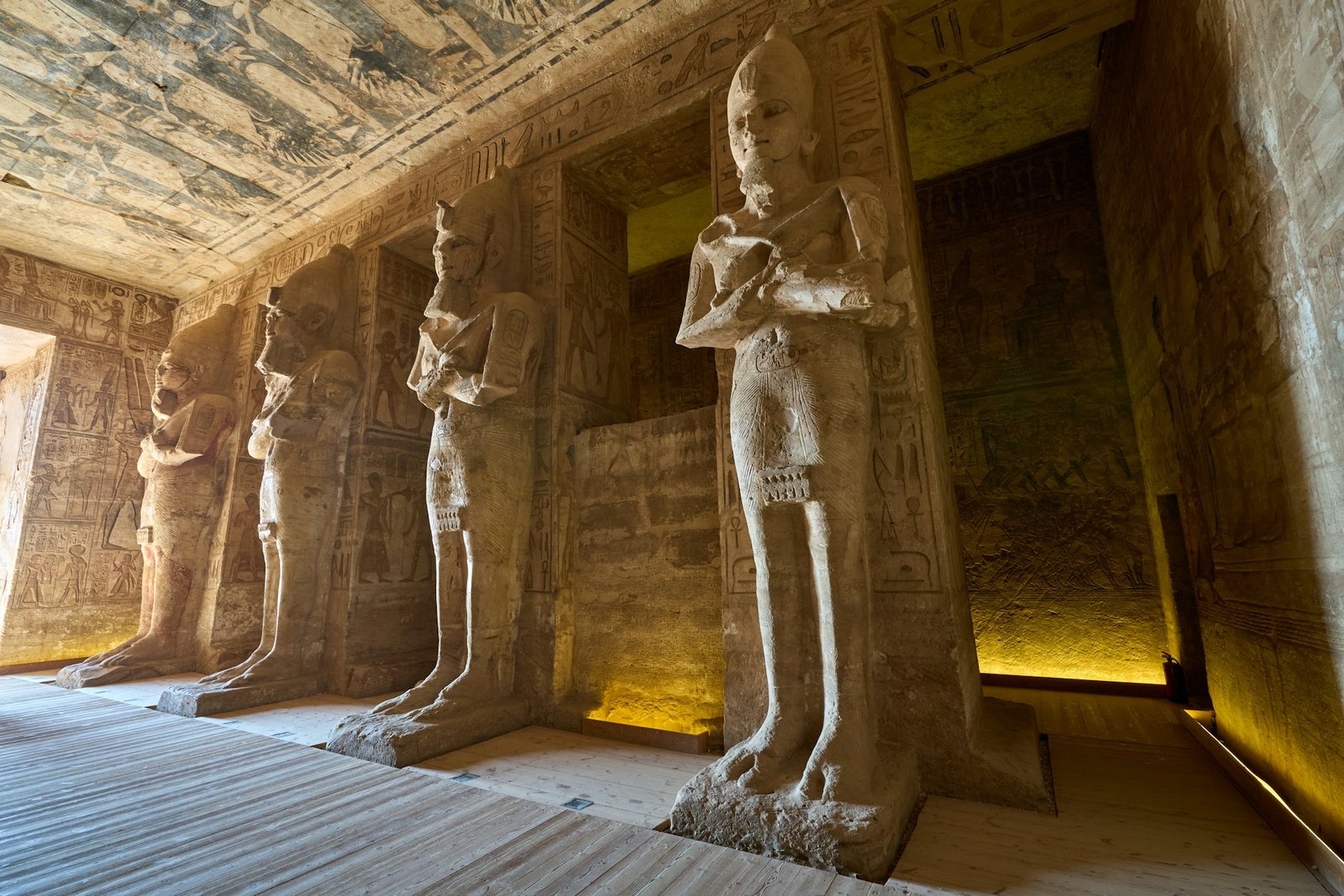 A photo of the interior of the Great Temple of Abu Simbel, showcasing the colossal statues of Ramses II and the intricate wall carvings.