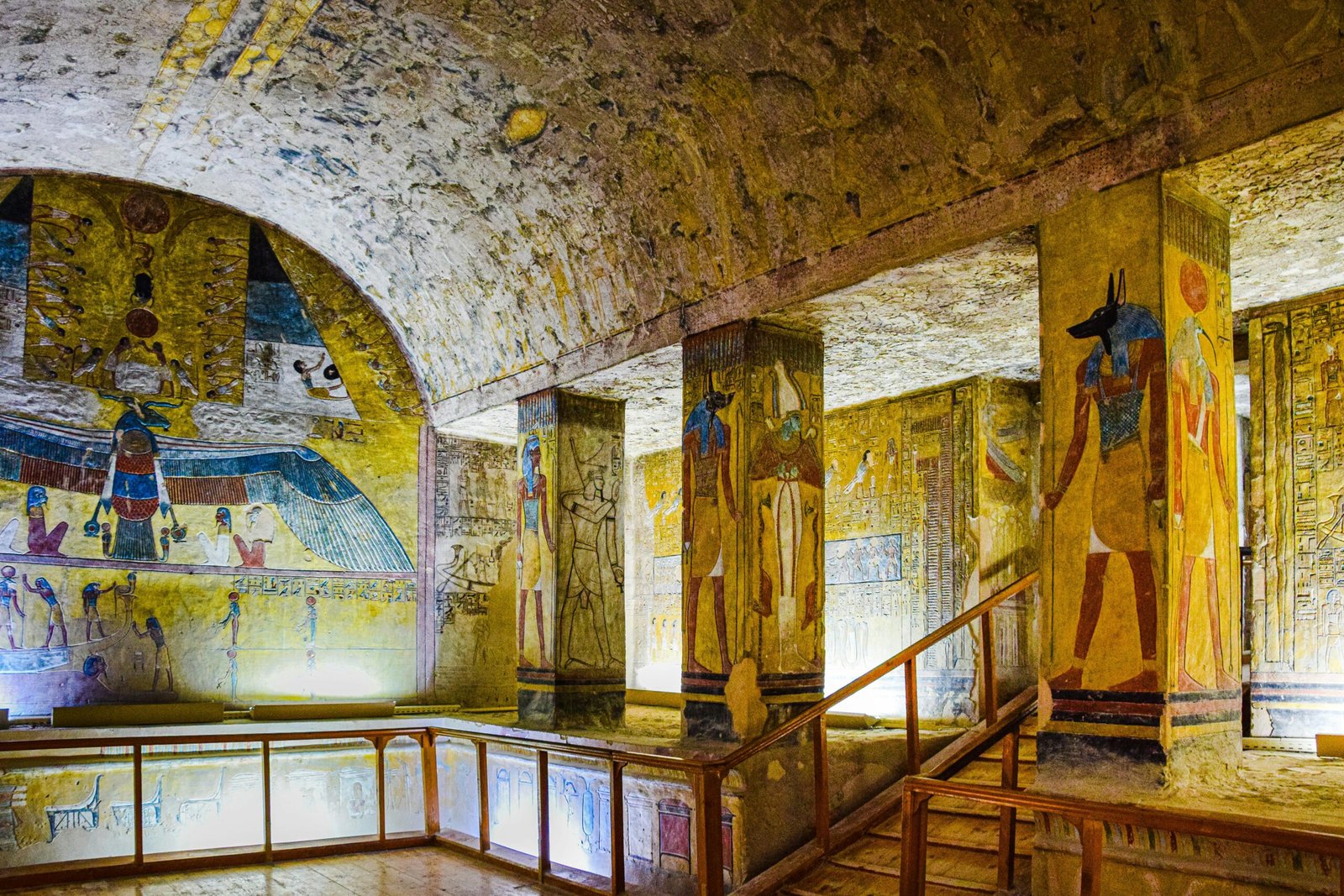  A photo of the interior of the Tomb of Ramses IV in the Valley of the Kings, showcasing the sarcophagus, the colorful wall paintings, and the pillars adorned with hieroglyphs.