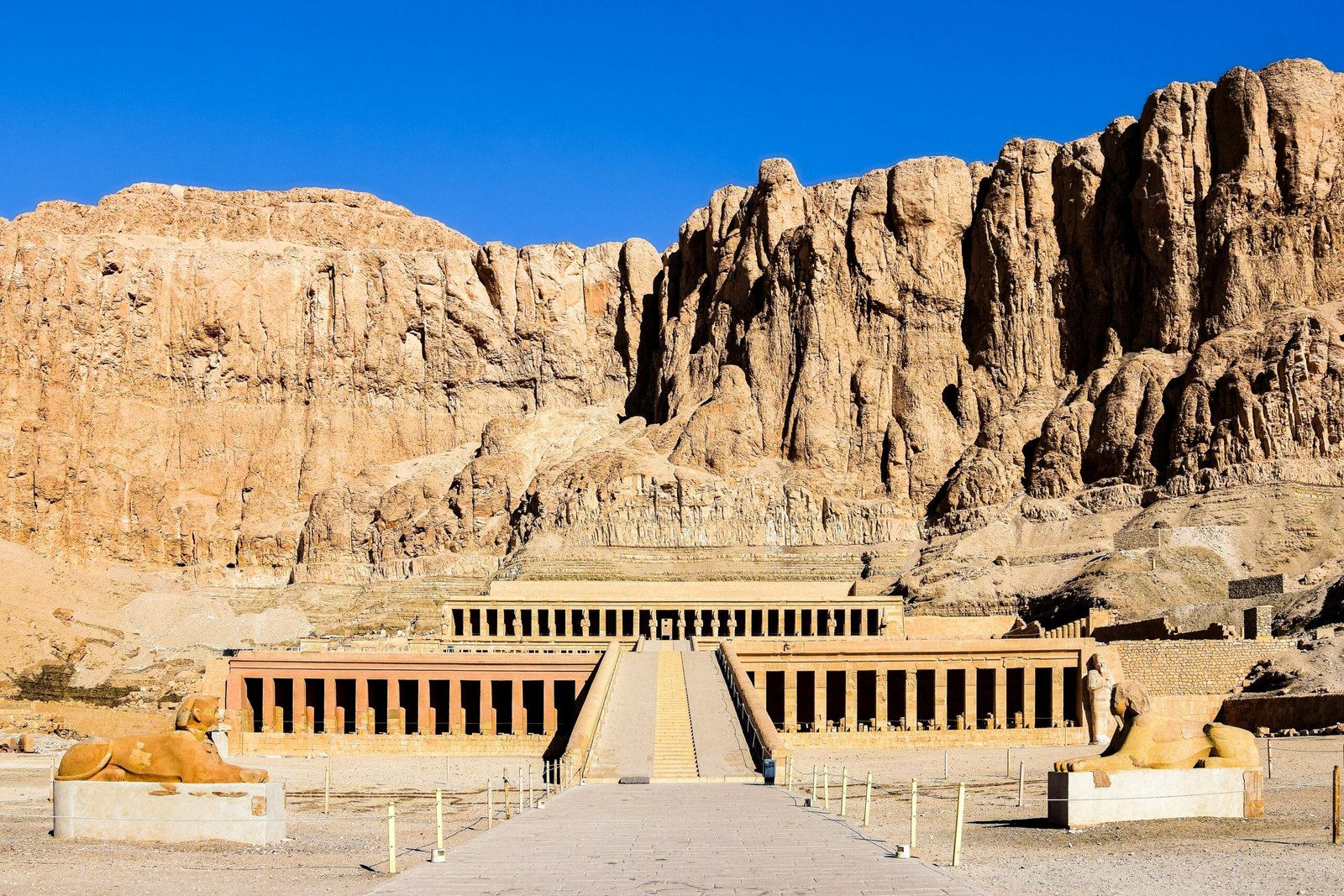 An aerial view of the Mortuary Temple of Hatshepsut in Deir el-Bahari, showcasing its terraced design and its integration into the surrounding cliffs.