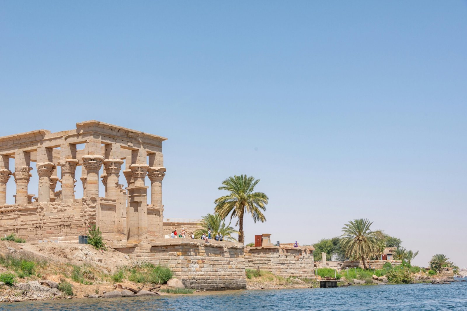 A photo of the Temple of Philae on Agilkia Island, showcasing the temple's intricate carvings, the pylon, and the surrounding water.