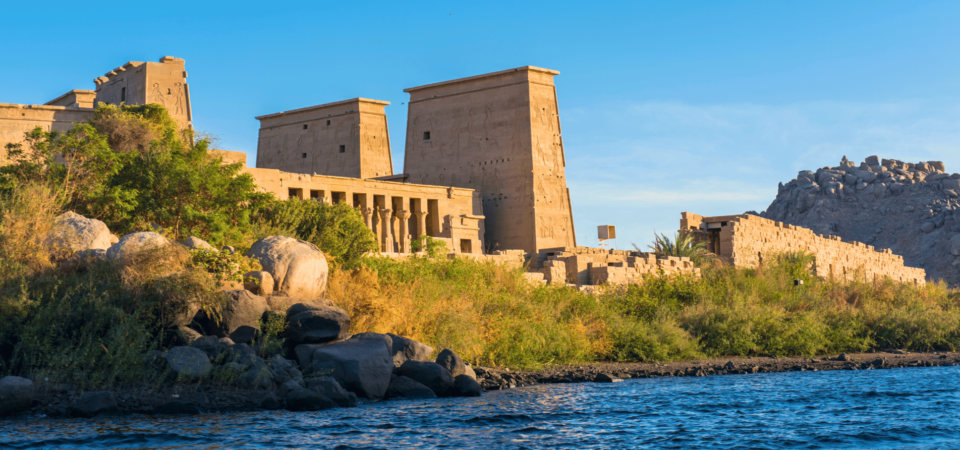 The Philae Temple surrounded by lush greenery and the calm waters of the Nile.