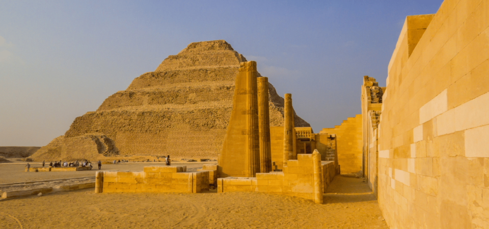 The Step Pyramid of Djoser, surrounded by ancient structures, glowing under a golden sunset at Saqqara.