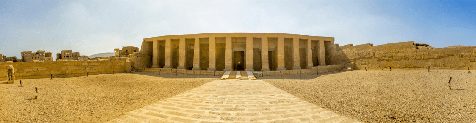 Panoramic view of the Temple of Seti I in Abydos, with a wide stone pathway leading to the grand entrance.