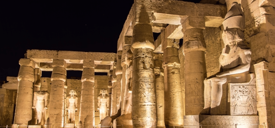 Luxor Temple illuminated at night with statues and columns glowing golden.