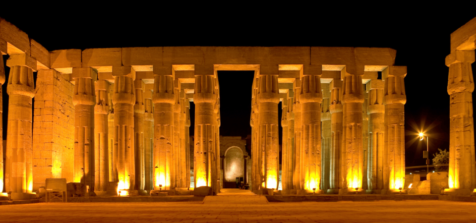 The illuminated columns of Luxor Temple glowing under the night sky.