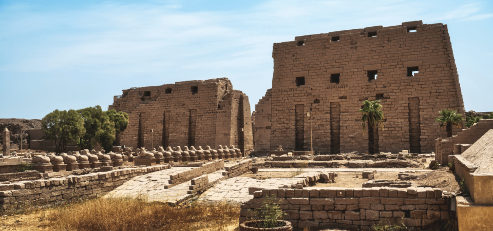 The Avenue of Sphinxes leading to the grand Karnak Temple in Luxor, under a serene blue sky.