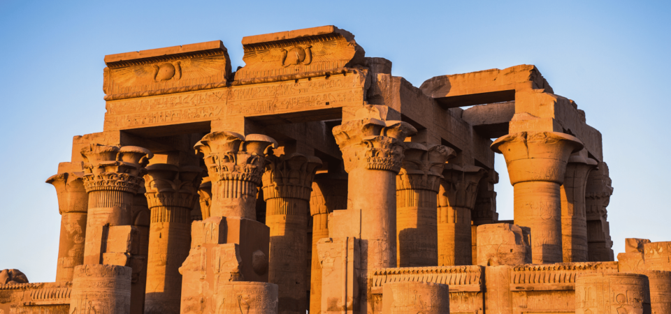 The illuminated facade of the Kom Ombo Temple at sunset, showcasing its detailed carvings and dual dedication.