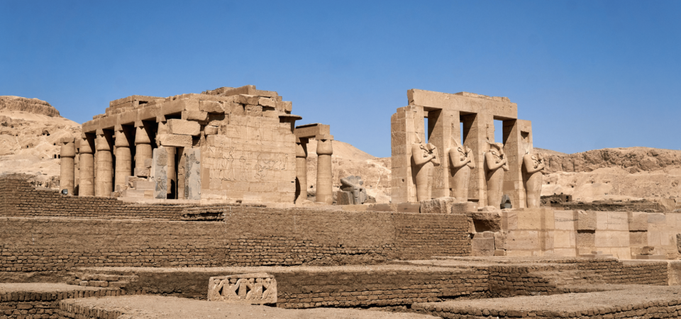 The ruins of the Ramesseum Temple in Luxor, Egypt, with colossal statues and remnants of ancient columns.