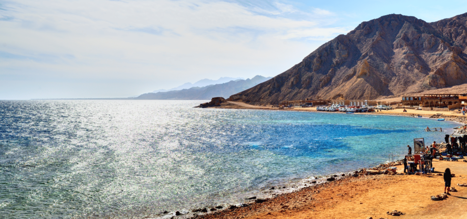 Shimmering waters of the Red Sea meeting rugged desert mountains in Dahab, Egypt.