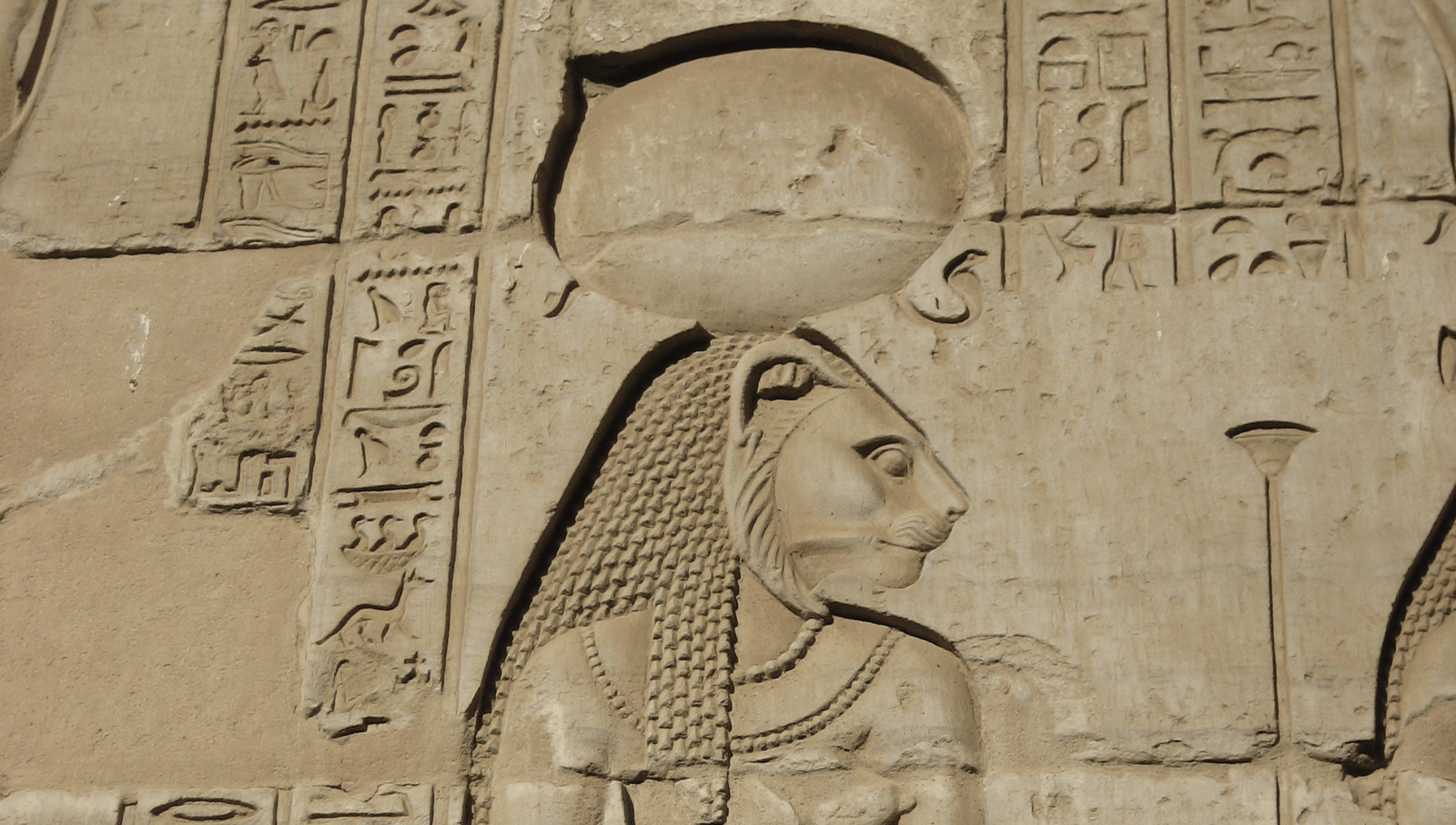 Ancient depiction of Sekhmet with sun disk in an Egyptian temple.