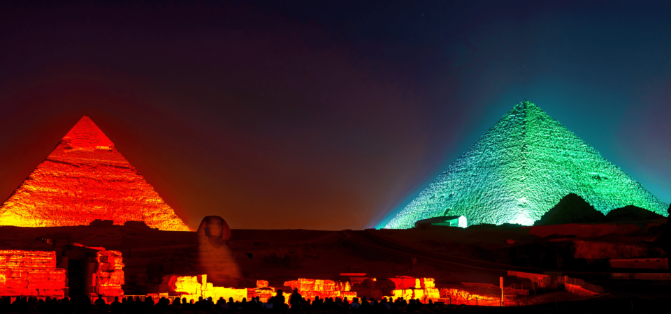 The Pyramids of Giza illuminated in colorful lights during the Sound and Light Show.