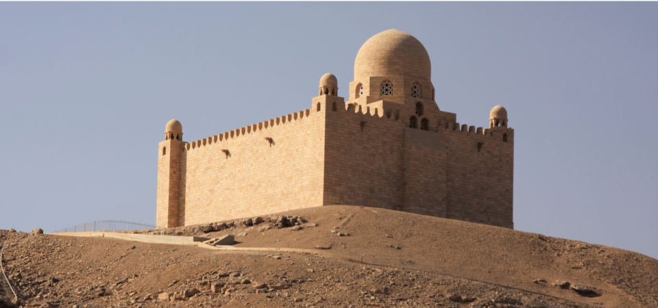 The Mausoleum of Aga Khan perched on a desert hill, illuminated by the golden rays of the sun.