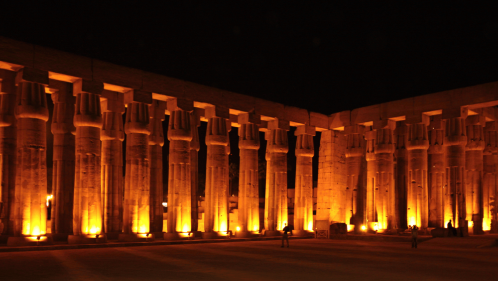 Luxor Temple's colonnade lit with golden lights at night.